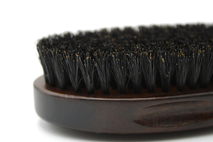 Close-up of a black bristle brush with a wooden handle on a white background